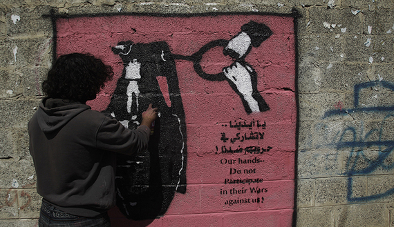 Artist Murad Subai paints a graffiti depicting a grenade on a street in Sanaa
