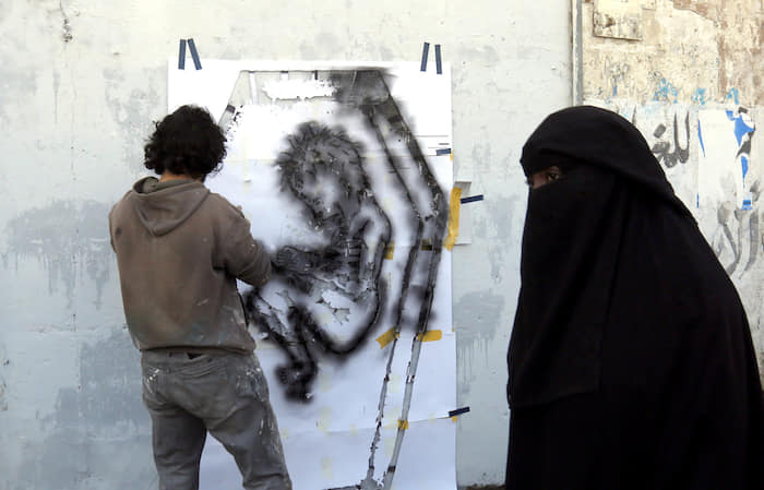 epa05595530 A picture made available on 21 October 2016 shows a Yemeni artist spraying a graffiti on a wall in protest against the ongoing conflict and the worsening economic situation in the war-affected country, in Sana’a, Yemen, 20 October 2016. According to reports, since March 2015, ongoing conflict and the Saudi-led airstrike campaign in Yemen have left 21.2 million - 82 percent of Yemen’s population - in dire need of humanitarian aid, including 9.9 million children.  EPA/YAHYA ARHAB